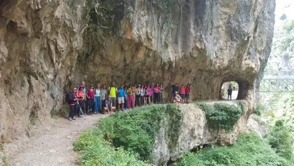 Grupo de excursionistas posa en la Ruta del Cares, superando la dificultad del terreno rocoso y los túneles.
